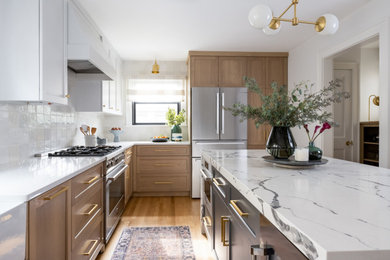 Small transitional l-shaped medium tone wood floor enclosed kitchen photo in New York with a farmhouse sink, shaker cabinets, light wood cabinets, quartz countertops, white backsplash, ceramic backsplash, stainless steel appliances, an island and white countertops
