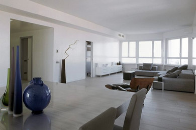 This is an example of an expansive modern loft-style living room in Milan with white walls, light hardwood floors, a concealed tv and white floor.