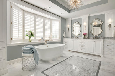 Huge transitional master white tile and marble tile marble floor, white floor, double-sink and tray ceiling bathroom photo in Minneapolis with recessed-panel cabinets, white cabinets, blue walls, an undermount sink, marble countertops, white countertops and a built-in vanity