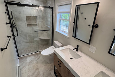 Mid-sized minimalist master gray tile and porcelain tile porcelain tile, gray floor and double-sink bathroom photo in Newark with brown cabinets, an undermount sink, white countertops, a one-piece toilet and a freestanding vanity