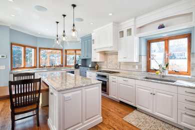 Example of a large transitional u-shaped medium tone wood floor eat-in kitchen design in Other with raised-panel cabinets, white cabinets, quartz countertops, paneled appliances and an island