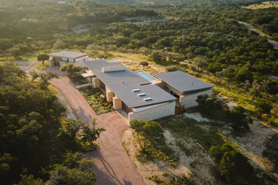 Mid-sized modern beige one-story stone house exterior idea in Austin with a shed roof, a metal roof and a gray roof