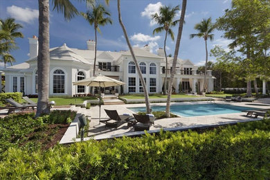Huge coastal white three-story adobe house exterior idea in Miami with a clipped gable roof and a tile roof