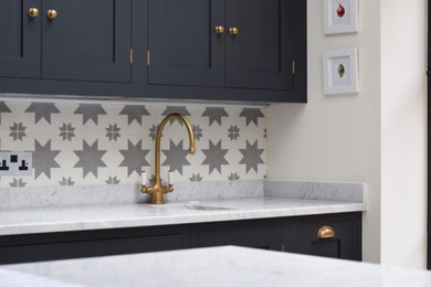 Design ideas for a mid-sized contemporary kitchen in London with blue cabinets, grey splashback, cement tile splashback and grey benchtop.