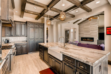 Inspiration for a large transitional u-shaped porcelain tile and beige floor eat-in kitchen remodel in Denver with a farmhouse sink, raised-panel cabinets, dark wood cabinets, limestone countertops, metallic backsplash, mosaic tile backsplash, stainless steel appliances, an island and beige countertops