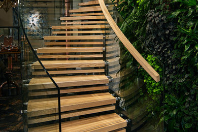 Expansive contemporary wood curved staircase in Wellington with wood risers and glass railing.