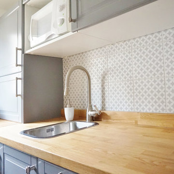 Une petite salle d'eau rose et une petite cuisine grise dans un immeuble ancien