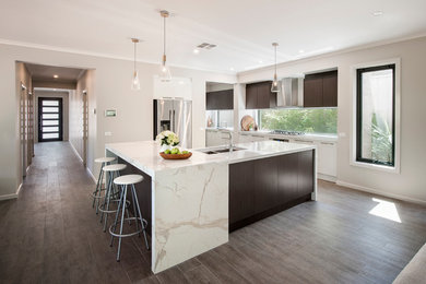 Large trendy l-shaped medium tone wood floor open concept kitchen photo in Other with an undermount sink, white cabinets, quartz countertops, white backsplash, stainless steel appliances, an island and flat-panel cabinets