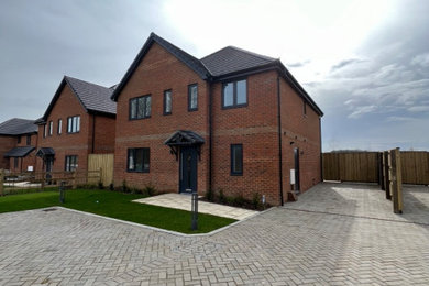 Large and red classic two floor front detached house in Kent with a hip roof, a tiled roof and a grey roof.