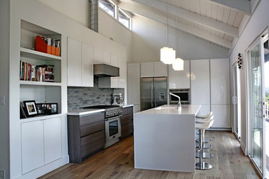 Inspiration for a mid-sized modern l-shaped open plan kitchen in San Francisco with a single-bowl sink, flat-panel cabinets, white cabinets, quartz benchtops, grey splashback, ceramic splashback, stainless steel appliances, light hardwood floors and with island.