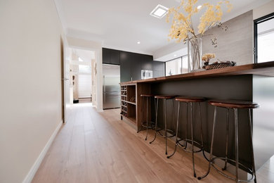 Design ideas for a mid-sized contemporary galley open plan kitchen in Perth with an undermount sink, flat-panel cabinets, black cabinets, wood benchtops, grey splashback, porcelain splashback, stainless steel appliances, laminate floors and with island.