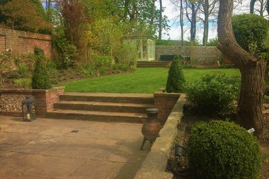 Diseño de jardín campestre de tamaño medio en verano en patio trasero con huerto, exposición total al sol, adoquines de piedra natural y con madera