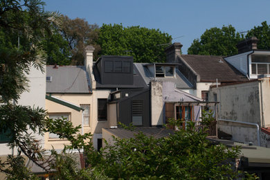 This is an example of a mid-sized modern three-storey grey house exterior in Sydney with metal siding, a flat roof and a metal roof.