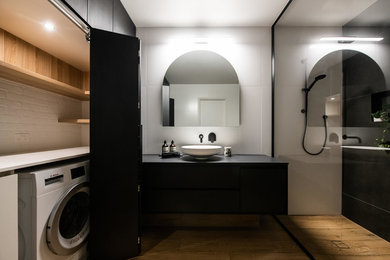 Large contemporary bathroom in Melbourne with an open shower, white tile, ceramic tile, black walls, porcelain floors, a vessel sink, engineered quartz benchtops, brown floor, an open shower, black benchtops, furniture-like cabinets and black cabinets.