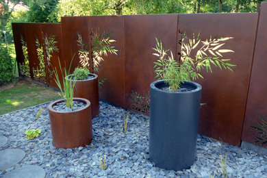 Idée de décoration pour un jardin design avec une clôture en métal.