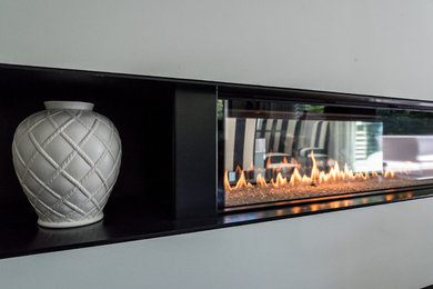Photo of a contemporary living room in Marseille with a two-sided fireplace and a plaster fireplace surround.