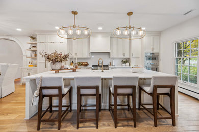 Large transitional galley light wood floor, beige floor and exposed beam eat-in kitchen photo in Cincinnati with an undermount sink, recessed-panel cabinets, beige cabinets, quartzite countertops, beige backsplash, quartz backsplash, stainless steel appliances, an island and beige countertops