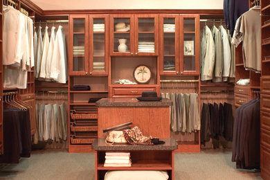 Large traditional gender-neutral walk-in wardrobe in Tampa with raised-panel cabinets, medium wood cabinets and carpet.