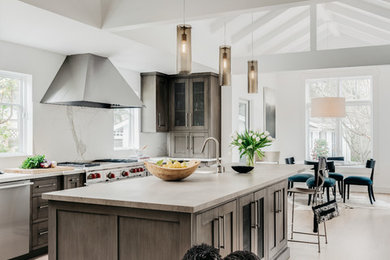 Large transitional l-shaped light wood floor, beige floor and exposed beam eat-in kitchen photo in San Francisco with recessed-panel cabinets, concrete countertops, white backsplash, stone slab backsplash, stainless steel appliances, an island, a farmhouse sink, multicolored countertops and medium tone wood cabinets