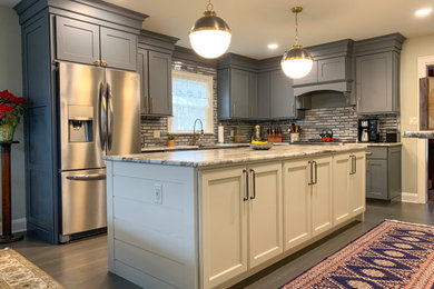 Mid-sized farmhouse l-shaped dark wood floor eat-in kitchen photo in Other with shaker cabinets, granite countertops, gray backsplash, subway tile backsplash, stainless steel appliances and an island