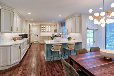 Eat-in kitchen - large transitional u-shaped dark wood floor and brown floor eat-in kitchen idea in Philadelphia with a farmhouse sink, recessed-panel cabinets, white cabinets, quartzite countertops, multicolored backsplash, ceramic backsplash, stainless steel appliances, a peninsula and white countertops