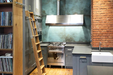 This is an example of a small industrial l-shaped enclosed kitchen in Other with a belfast sink, shaker cabinets, grey cabinets, quartz worktops, blue splashback, ceramic splashback, stainless steel appliances, light hardwood flooring and grey worktops.