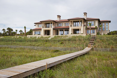 Inspiration for a large mediterranean beige two-story stucco house exterior remodel in Jacksonville with a hip roof and a shingle roof