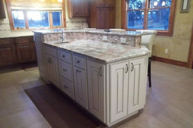 Example of a classic l-shaped porcelain tile and beige floor eat-in kitchen design in Other with a farmhouse sink, raised-panel cabinets, distressed cabinets, laminate countertops, beige backsplash, mosaic tile backsplash, stainless steel appliances and an island