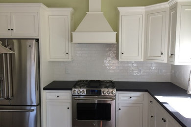 Mid-sized minimalist l-shaped medium tone wood floor eat-in kitchen photo in Orange County with shaker cabinets, white cabinets, an island, a single-bowl sink, granite countertops, white backsplash, porcelain backsplash and stainless steel appliances