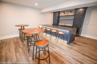 Large transitional walk-out vinyl floor basement photo in Other with a bar, beige walls and no fireplace