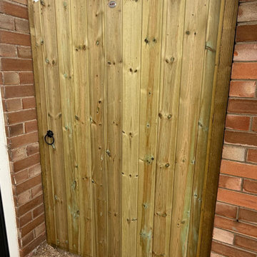 Arched Top Timber Side Gate Hung Between Brick Piers