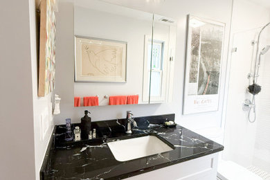Example of a minimalist master white tile and porcelain tile mosaic tile floor, multicolored floor and single-sink alcove shower design in Boston with flat-panel cabinets, white cabinets, a two-piece toilet, white walls, an undermount sink, quartz countertops, a hinged shower door, black countertops, a niche and a built-in vanity
