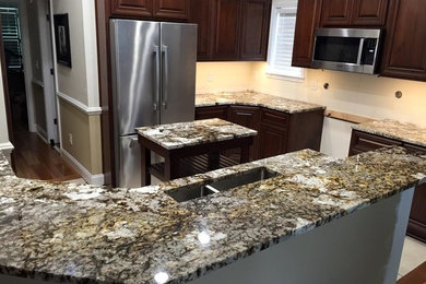 Example of a mid-sized classic l-shaped enclosed kitchen design in Other with an undermount sink, raised-panel cabinets, dark wood cabinets, granite countertops, beige backsplash, stainless steel appliances and an island