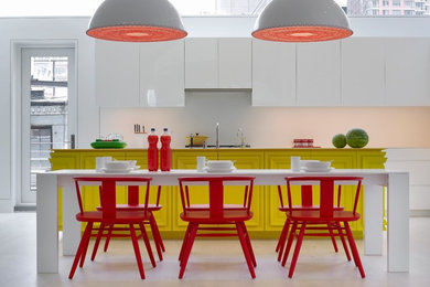 Photo of a contemporary eat-in kitchen in New York with recessed-panel cabinets, yellow cabinets, white splashback and white floor.