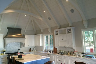 Mid-sized arts and crafts u-shaped dark wood floor eat-in kitchen photo in San Francisco with a drop-in sink, raised-panel cabinets, white cabinets, marble countertops, white backsplash, subway tile backsplash, stainless steel appliances and an island