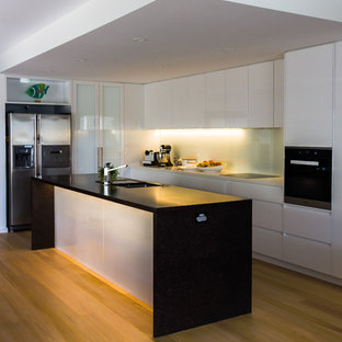Large contemporary kitchen pantry remodeling - Inspiration for a large contemporary l-shaped light wood floor kitchen pantry remodel in Newcastle - Maitland with an undermount sink, flat-panel cabinets, white cabinets, quartz countertops, white backsplash, glass sheet backsplash, black appliances and an island