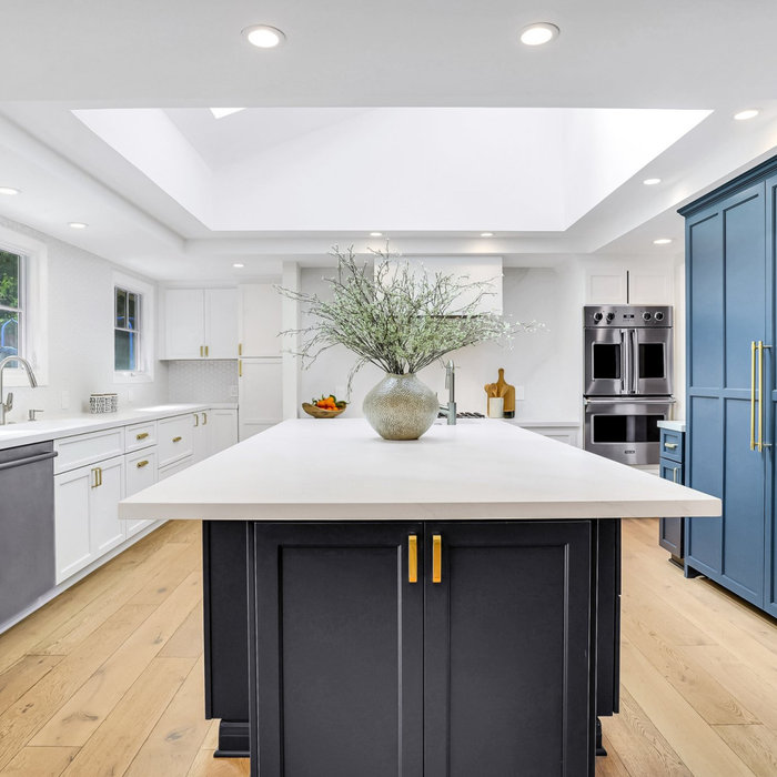Example of a transitional u-shaped light wood floor and beige floor kitchen design in San Francisco with recessed-panel cabinets, white cabinets, white backsplash, stainless steel appliances, an islan