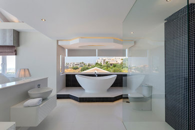 Expansive contemporary master bathroom in Other with raised-panel cabinets, white cabinets, a freestanding tub, a curbless shower, a two-piece toilet, white walls and a vessel sink.