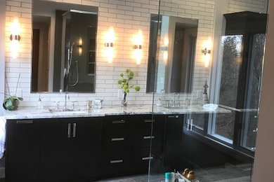 Example of a large trendy master white tile and ceramic tile cement tile floor and brown floor double shower design in St Louis with flat-panel cabinets, dark wood cabinets, a one-piece toilet, white walls, an undermount sink, marble countertops, a hinged shower door and white countertops