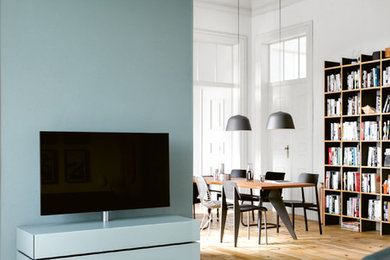 Mittelgroße, Offene Moderne Bibliothek ohne Kamin mit weißer Wandfarbe, gebeiztem Holzboden, freistehendem TV und beigem Boden in Frankfurt am Main