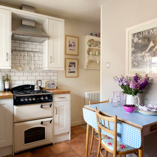 Exemple d'une cuisine américaine victorienne avec un placard avec porte à panneau encastré, des portes de placard blanches, un plan de travail en bois, une crédence blanche, une crédence en carrelage métro et un électroménager blanc.