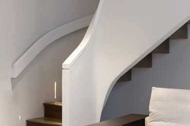 Inspiration for a modern wood curved staircase in London with wood risers.