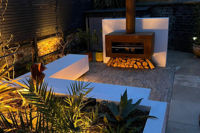 Design ideas for a world-inspired garden in Sussex with a fireplace, natural stone paving and a wood fence.