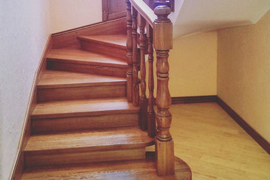 На фото: изогнутая деревянная лестница среднего размера с деревянными ступенями и деревянными перилами