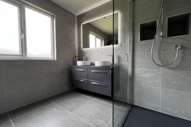 Inspiration for a medium sized modern ensuite bathroom in Essex with flat-panel cabinets, grey cabinets, a double shower, grey tiles, grey floors, an open shower, grey worktops, feature lighting, double sinks and a floating vanity unit.