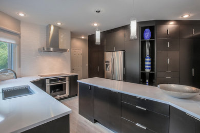 Inspiration for a large transitional u-shaped light wood floor open concept kitchen remodel in Kansas City with an undermount sink, flat-panel cabinets, dark wood cabinets, quartzite countertops, white backsplash, ceramic backsplash, stainless steel appliances and an island