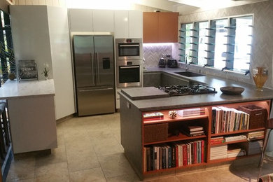 Mid-sized eclectic u-shaped kitchen pantry in Darwin with a drop-in sink, flat-panel cabinets, blue cabinets, solid surface benchtops, grey splashback, mosaic tile splashback, stainless steel appliances, slate floors and multiple islands.