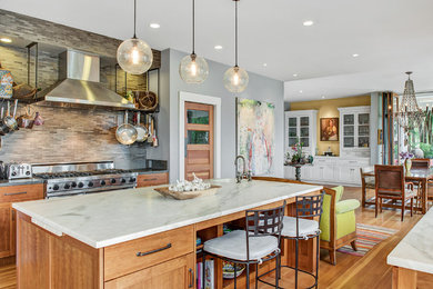 This is an example of a transitional galley kitchen in San Francisco with an undermount sink, shaker cabinets, medium wood cabinets, grey splashback, mosaic tile splashback, stainless steel appliances, medium hardwood floors, with island, brown floor and white benchtop.