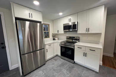 Inspiration for a mid-sized transitional l-shaped slate floor and gray floor eat-in kitchen remodel in Manchester with a double-bowl sink, shaker cabinets, white cabinets, quartz countertops, stainless steel appliances, a peninsula and white countertops