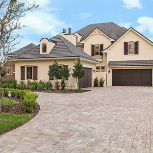 Foto på ett mycket stort vintage beige hus, med två våningar, stuckatur, sadeltak och tak med takplattor